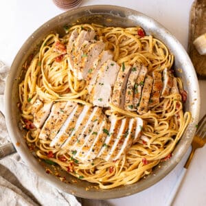 Creamy pasta in a pan topped with golden brown chicken.