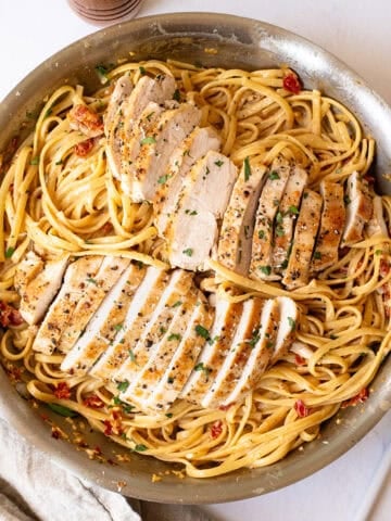 Creamy pasta in a pan topped with golden brown chicken.