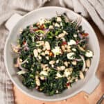 Kale and Cannellini Bean salad in a bowl topped with pine nuts.