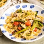 Pasta primavera with broccoli, asparagus, and cherry tomatoes in a bowl.