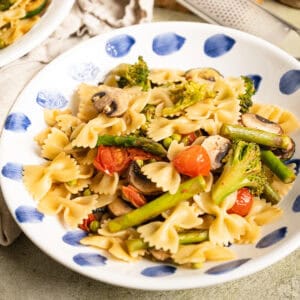Pasta primavera with broccoli, asparagus, and cherry tomatoes in a bowl.