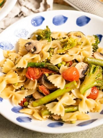 Pasta primavera with broccoli, asparagus, and cherry tomatoes in a bowl.