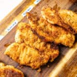 Chicken cutlets on a cutting board.