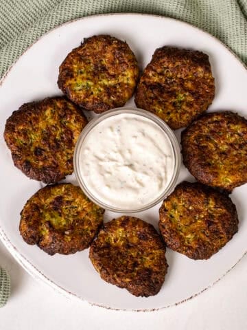 Air fryer zucchini fritters on a plate with aioli.