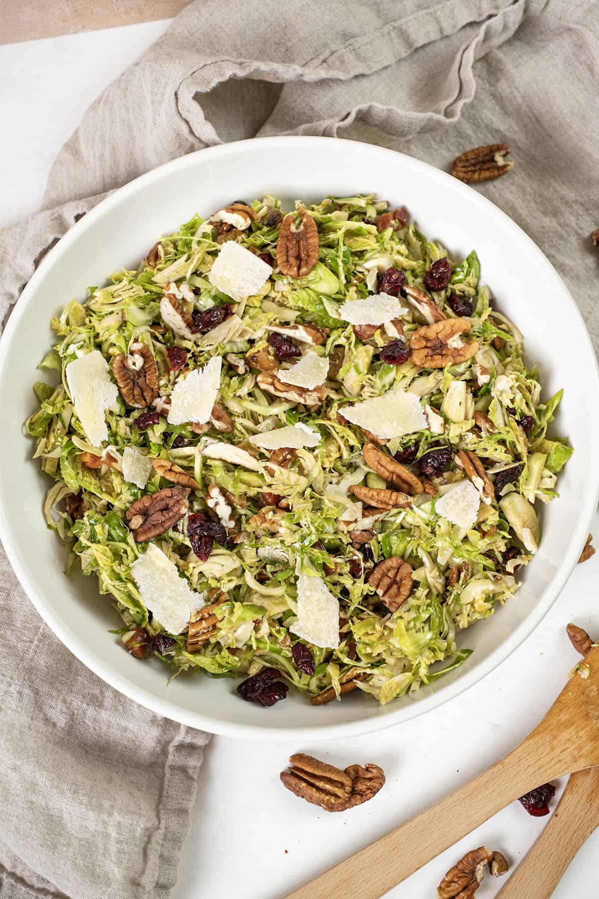 Brussels sprouts salad in a bowl topped with dried cranberries and pecans.