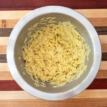 Combining orzo with olive oil to cool.