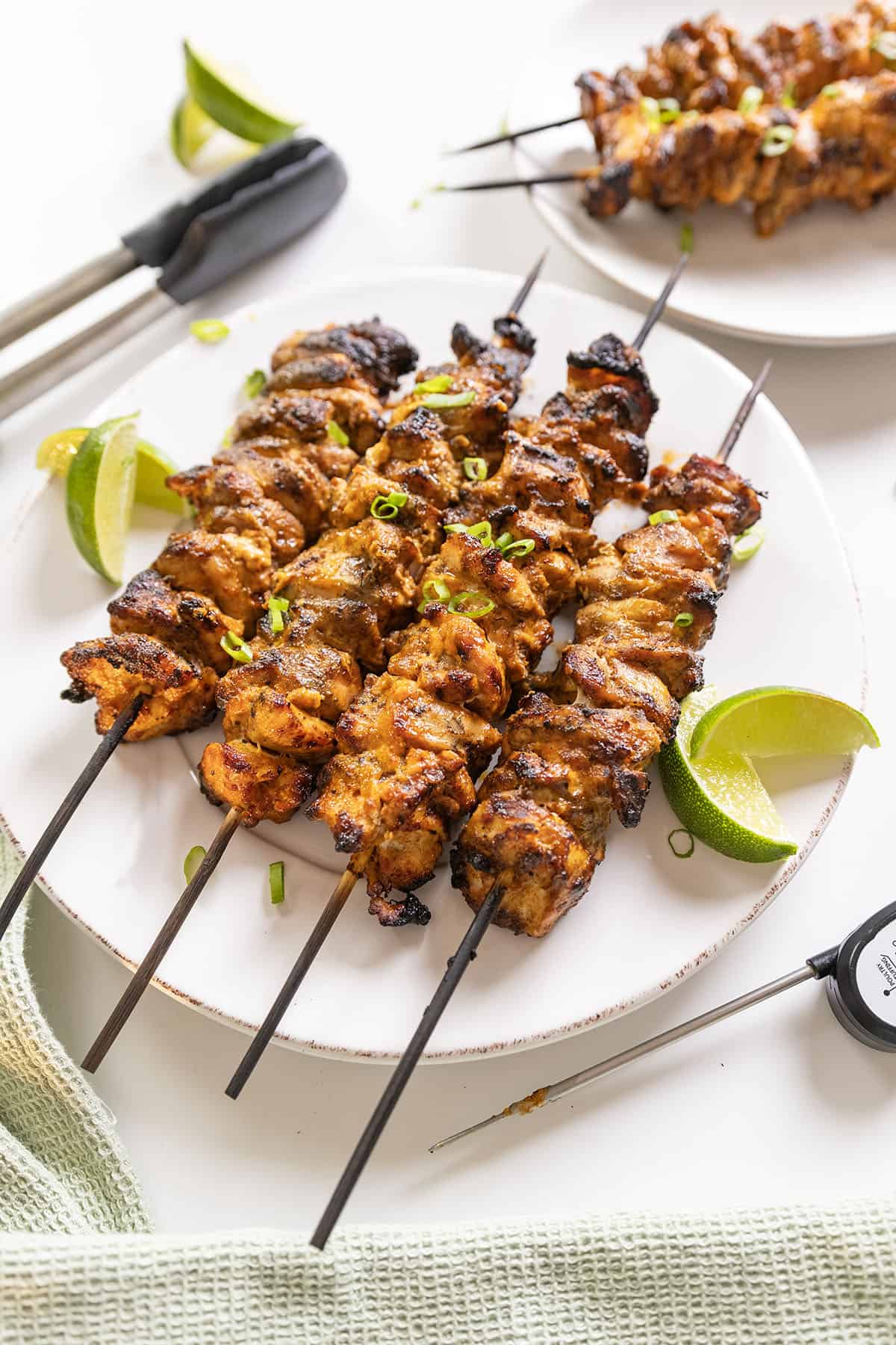 Bang Bang Chicken skewers with limes on the side.