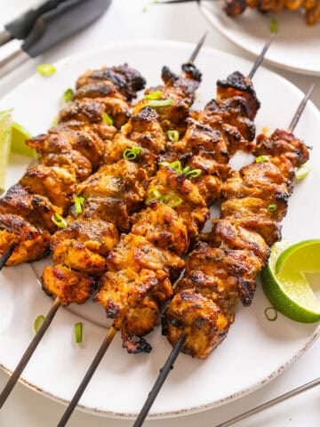 Bang Bang Chicken skewers with limes on the side.