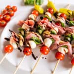 Caprese skewers on a plate drizzled with balsamic glaze.