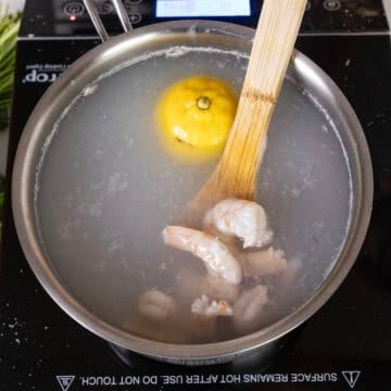 Boiling shrimp in a pot with a lemon.