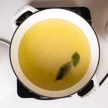 Whisking together cold water, olive oil, salt, bay leaves, and polenta.