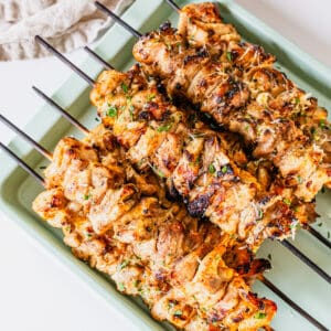 Garlic parm chicken skewers on a baking pan.