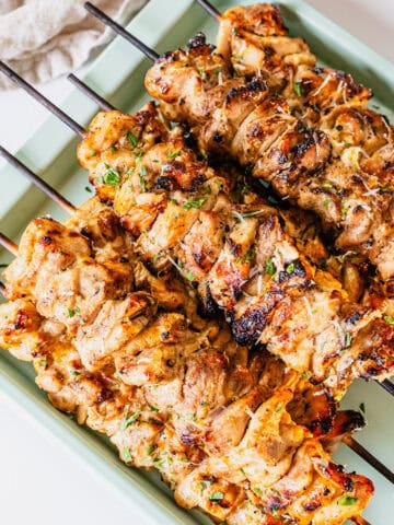 Garlic parm chicken skewers on a baking pan.