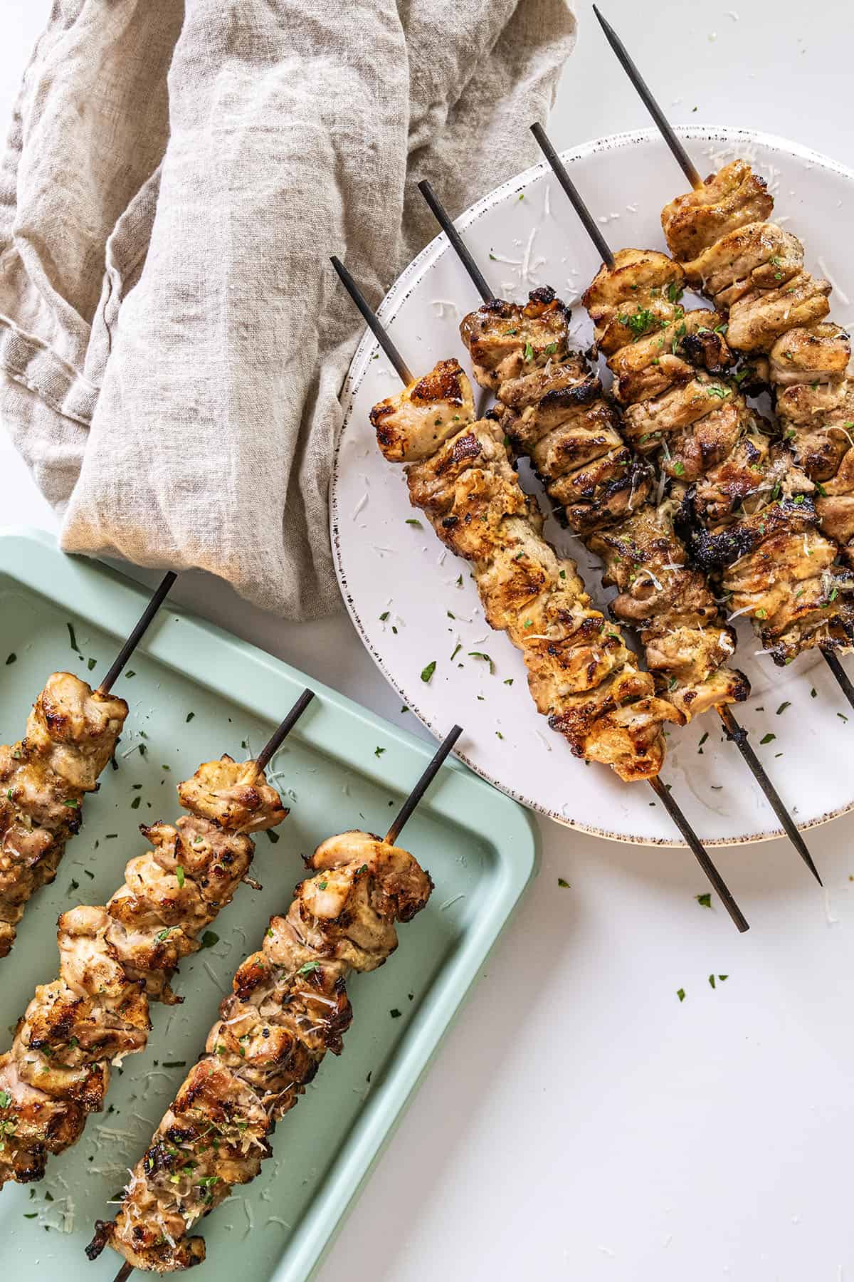 Garlic parm chicken skewers on a plate basted with parm sauce.
