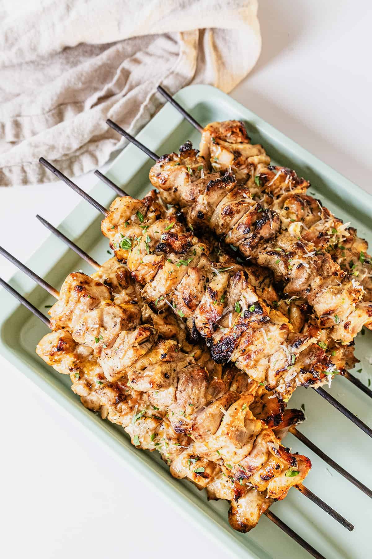 Garlic parm chicken skewers on a baking pan basted with parm sauce.