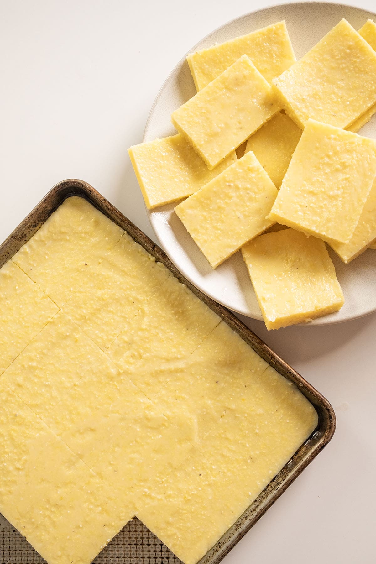 Chilled polenta cut into squares on a plate.