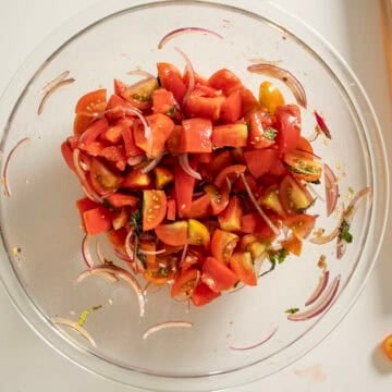 Combining tomatoes, red onion, basil, and dressing.