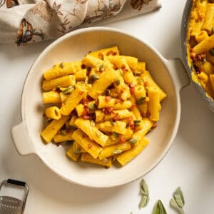 Pumpkin pasta in a bowl topped with pumpkin seeds and pancetta.