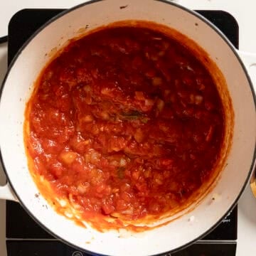 Marinara simmering in a pot with onions and garlic.