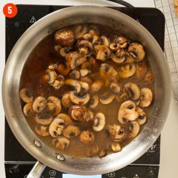 Mushrooms simmering in marsala wine and broth in a pan.