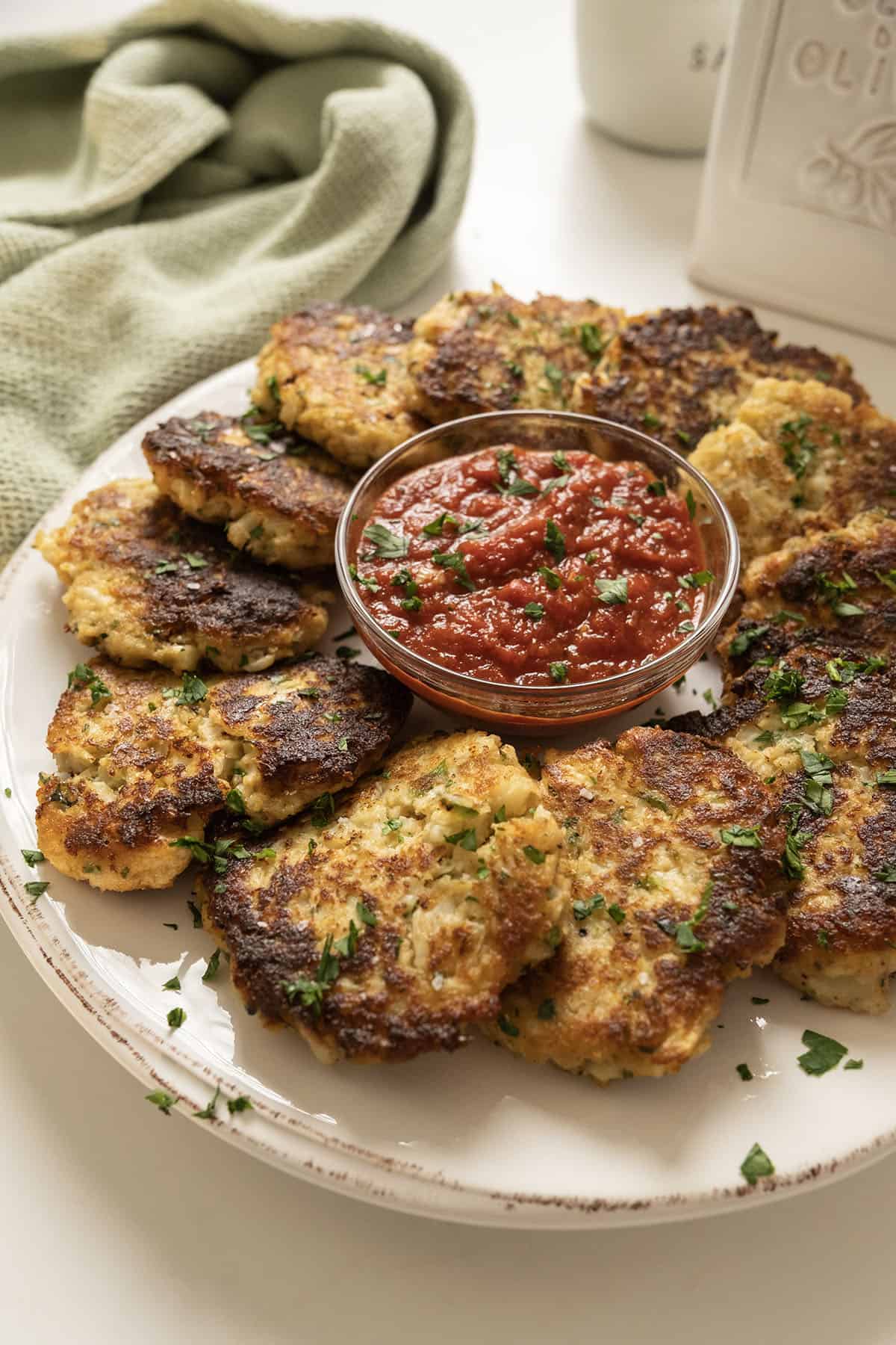 Fried cauliflower cakes on a plate with marinara sauce.