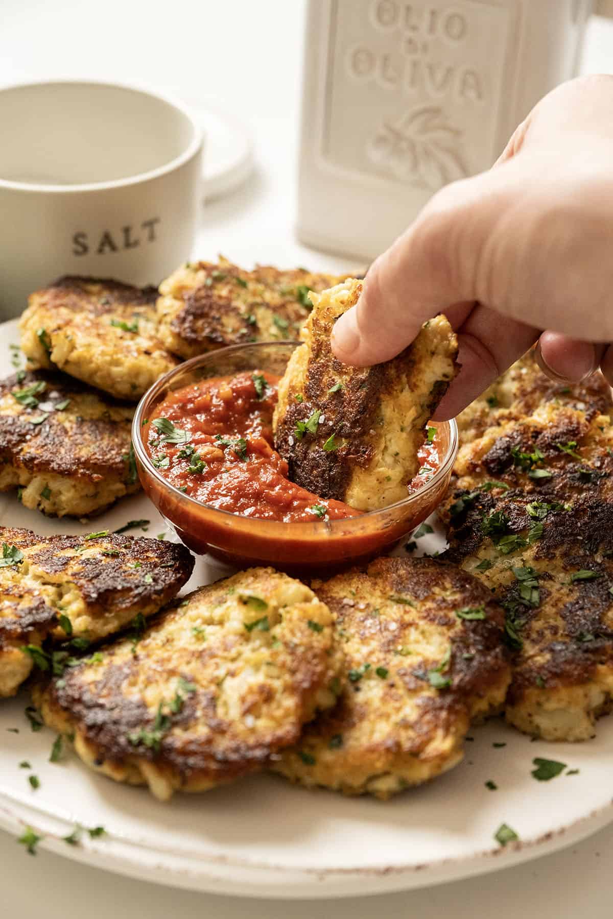 Fried cauliflower cakes on a plate with marinara sauce.