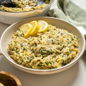 Lemon spinach orzo in a bowl topped with lemon garnish.