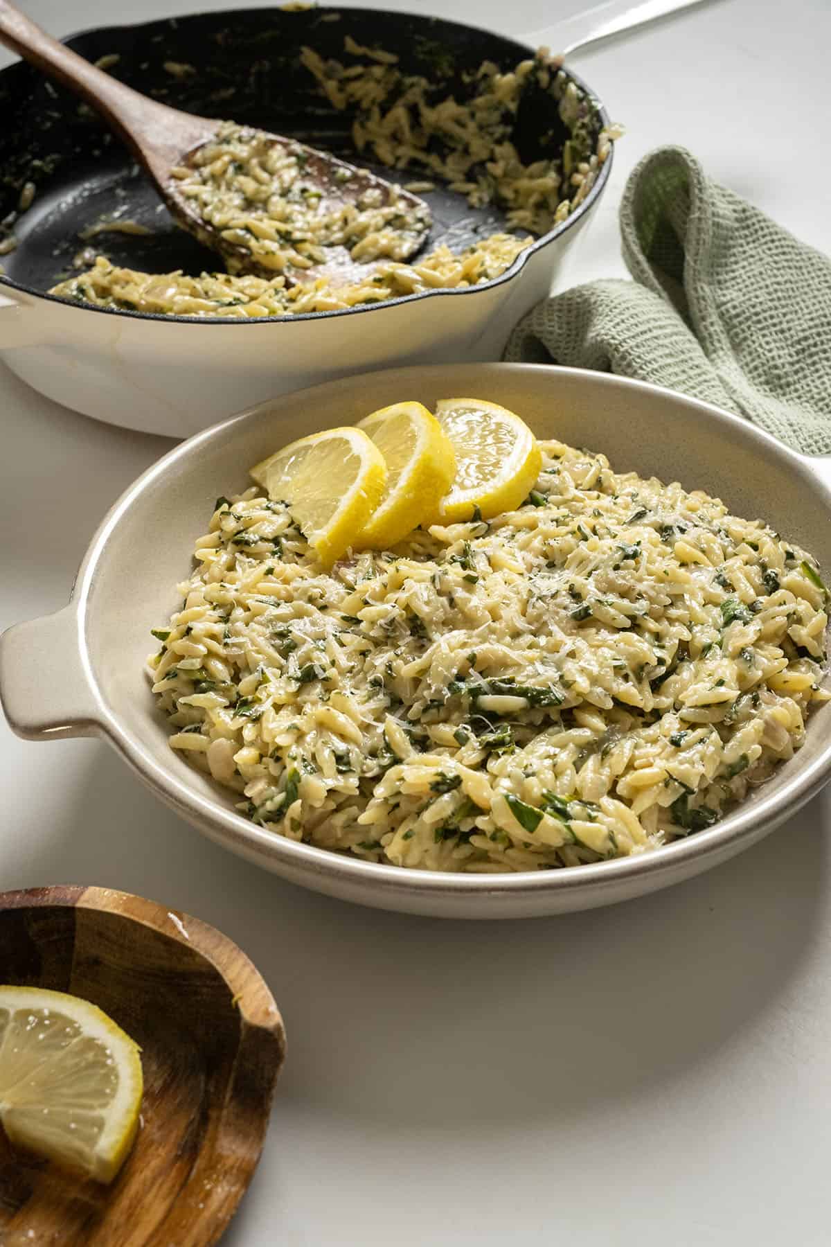 Lemon spinach orzo in a bowl topped with lemon garnish.