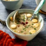 New england clam chowder in a bowl garnished with chives and oyster crackers.
