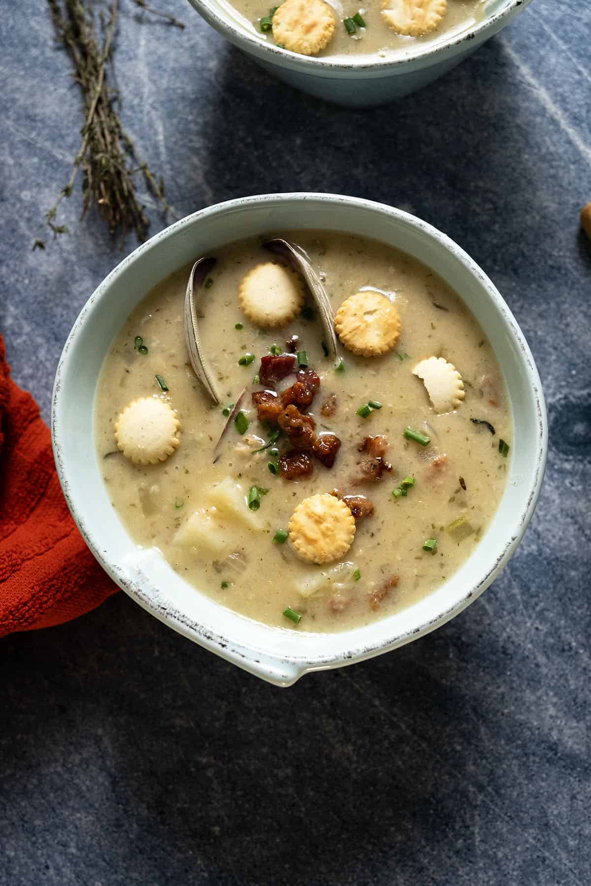New england clam chowder in a bowl garnished with chives and oyster crackers.