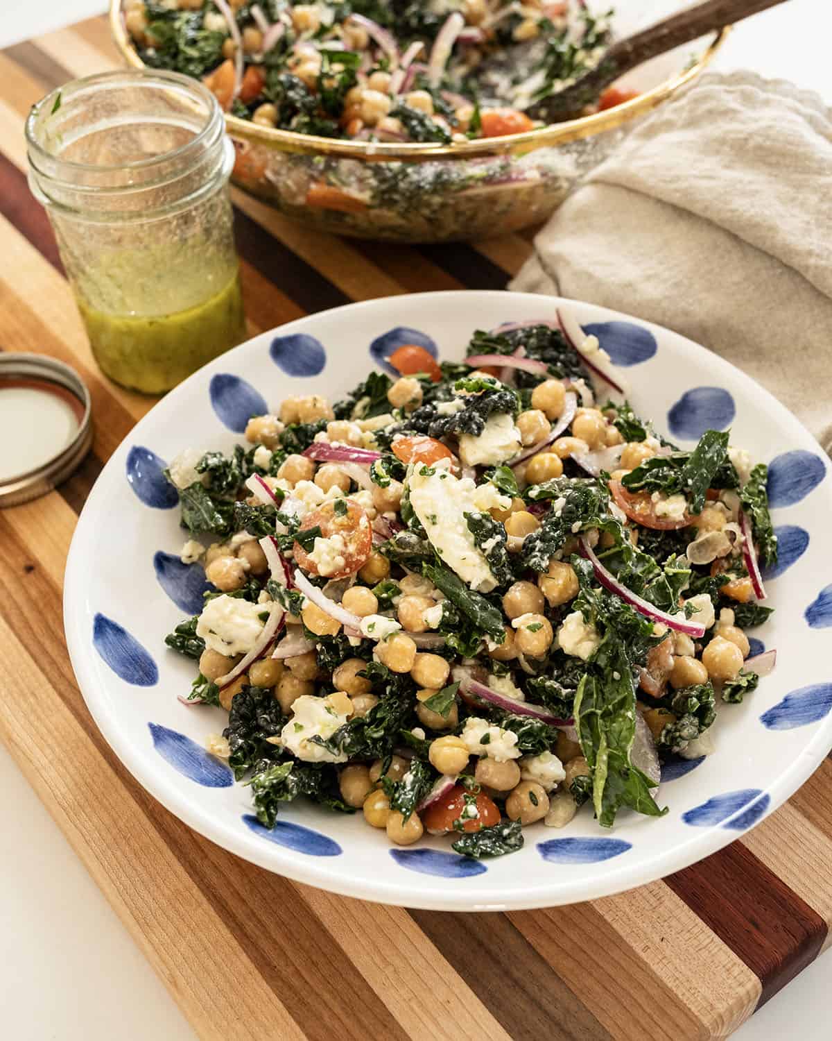Garbanzo bean kale salad in a bowl with mason jar of extra dressing.
