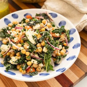 Garbanzo bean kale salad in a bowl with mason jar of extra dressing.