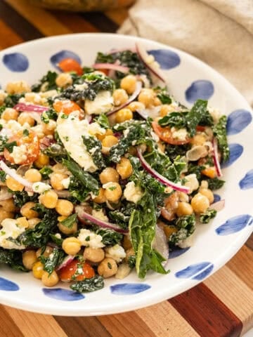Garbanzo bean kale salad in a bowl with mason jar of extra dressing.