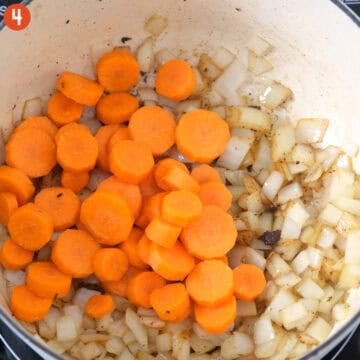 Sauteing carrots and onions in a pot.