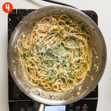 Spaghetti with garlic and oil in a pan topped with parsley and parmesan.