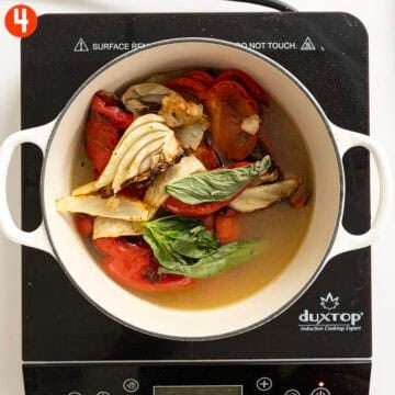 Roasted vegetables and broth in a dutch oven.