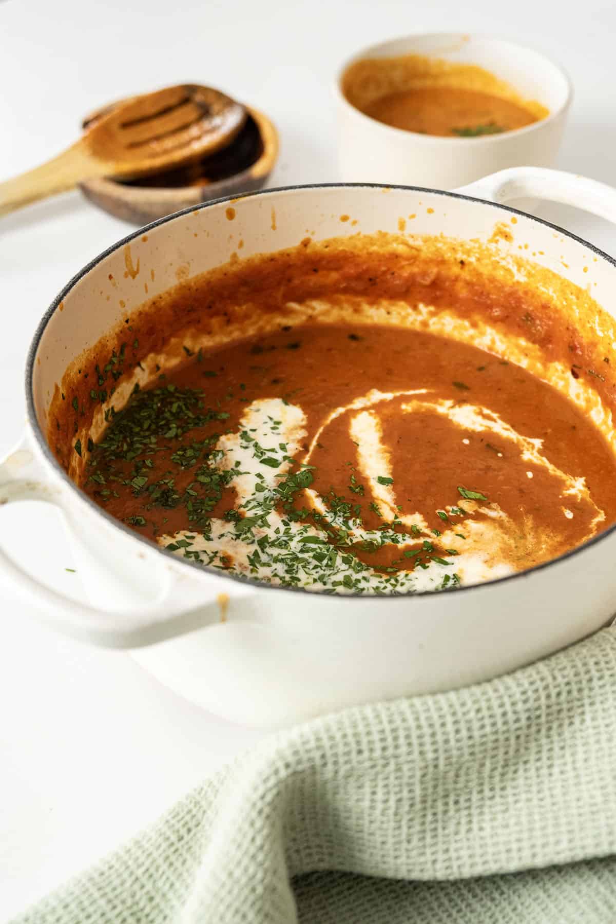 Roasted red pepper soup drizzled with cream and garnished with parsley.