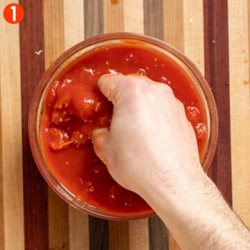 Hand crushing tomatoes.