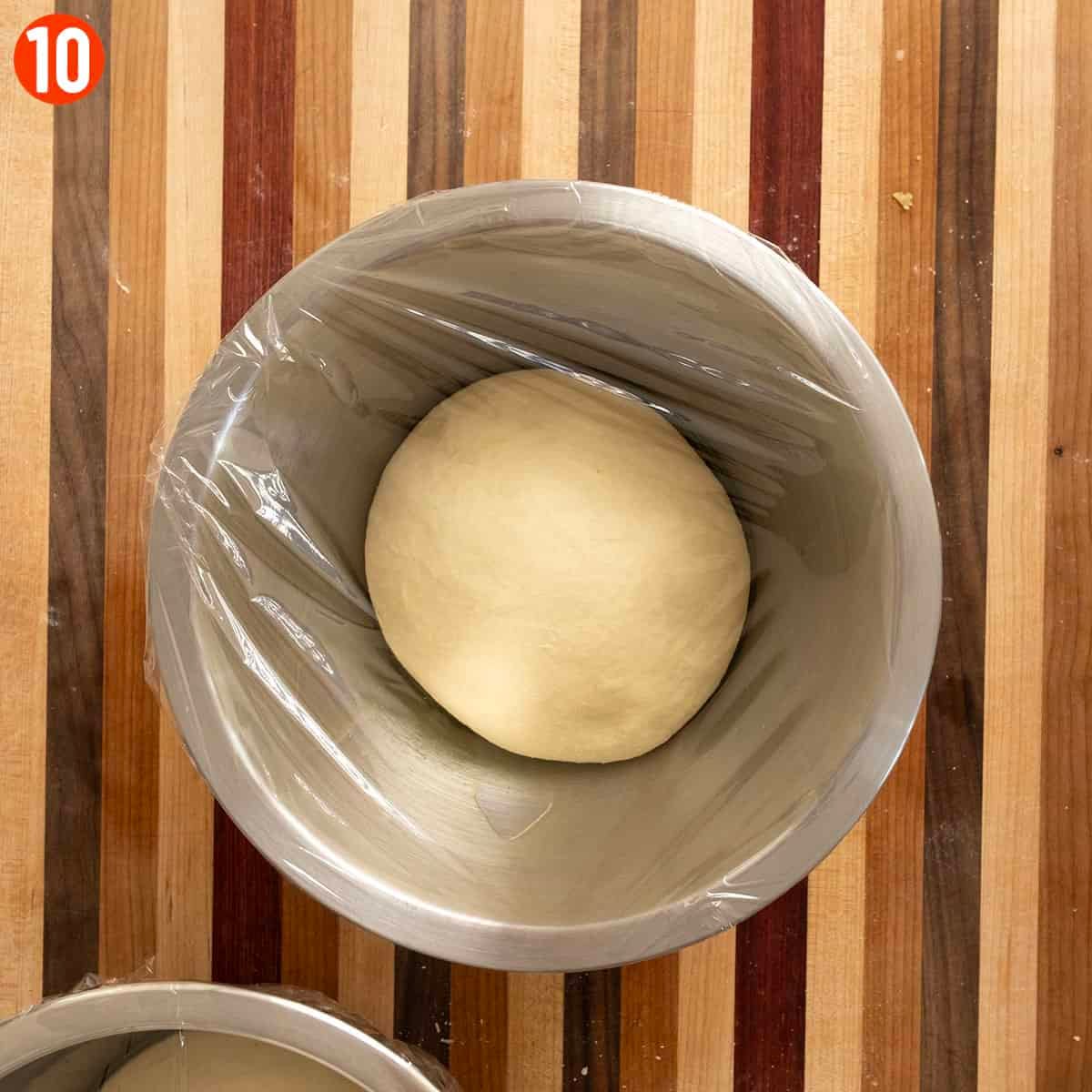Placing NY pizza dough in a bowl.