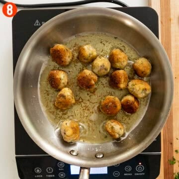 Golden-brown eggplant meatballs in a frying pan.