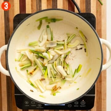 Sauteing spring onions in a pot.