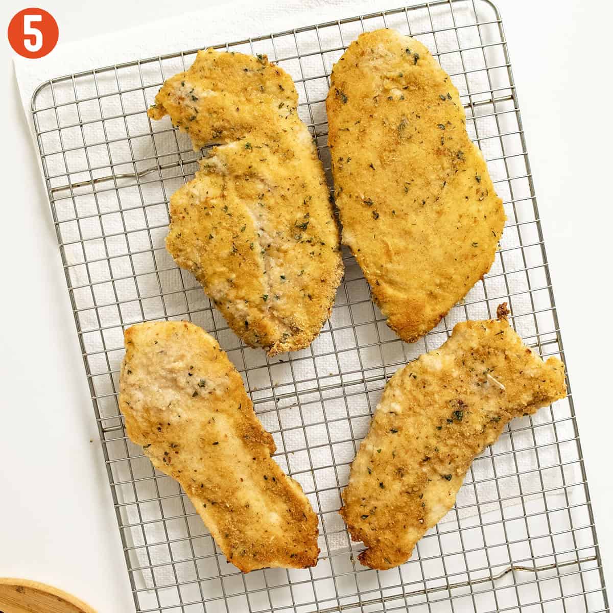 Chicken cutlets on a cooling rack.