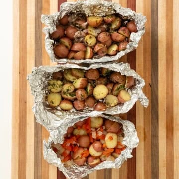 Grilled foil potatoes on a cutting board.