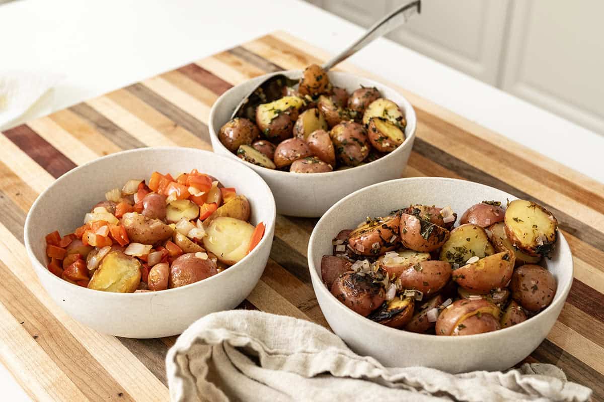 Foil potatoes 3 ways on a cutting board.