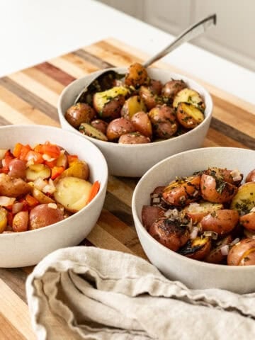 Foil potatoes 3 ways on a cutting board.