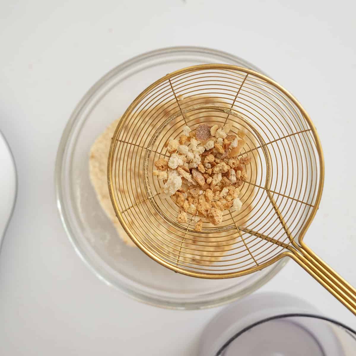 Removing larger pieces of bread from the processed breadcrumbs.