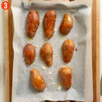 Sweet potatoes placed on a baking tray, cut side down.