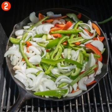 Peppers and onions in a cast iron pan.