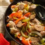 Grilled sausage and peppers in a cast iron pan.