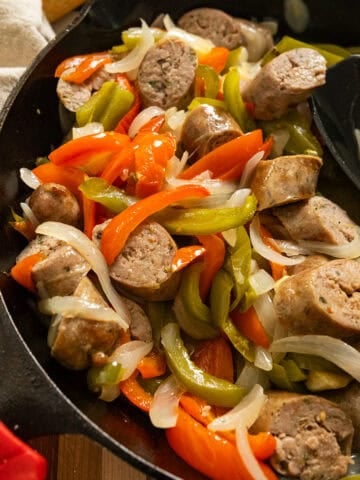 Grilled sausage and peppers in a cast iron pan.